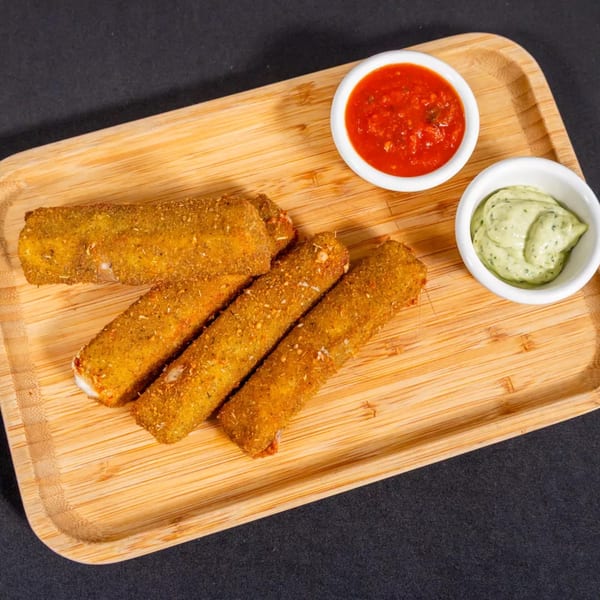 Four golden-brown mozzarella sticks on a wooden tray with red marinara and green pesto dips.