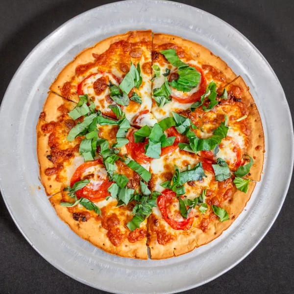 A Sorianos Pizzeria Margherita pizza with fresh basil and sliced tomatoes on a metal tray.