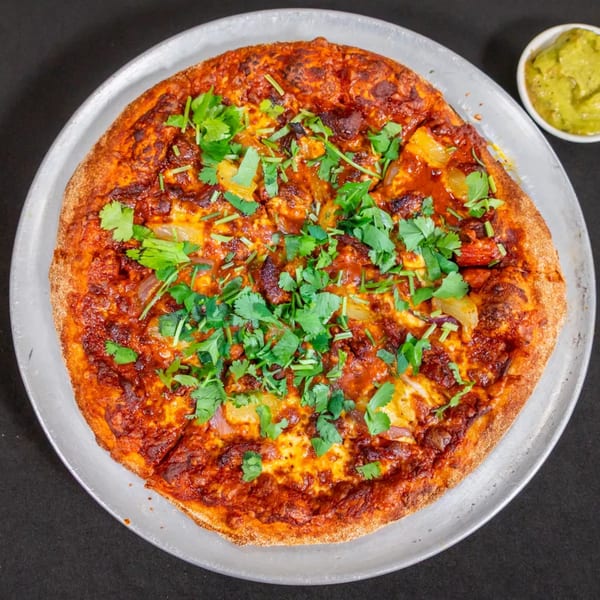 Sorianos Pizzeria's pizza with red sauce, cheese, pineapple, red onion, and cilantro, with guacamole.